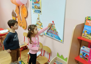 Dzieci na tablicy uzupełniają obrazkami piramidę zdrowego odżywiania się