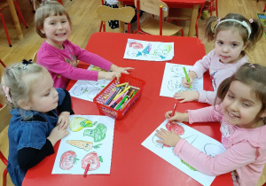 Dzieci przy stoliku kolorują zdrowe produkty żywnościowe