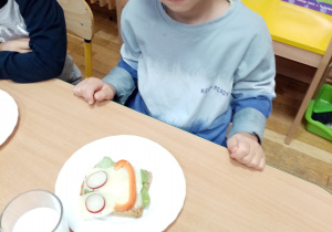 Chłopiec prezentuje przygotowaną przez siebie kanapkę.
