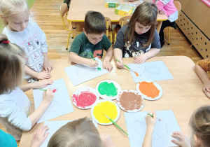 Dzieci powstałymi farbami malują liście