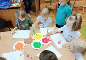 Dzieci powstałymi farbami malują liście