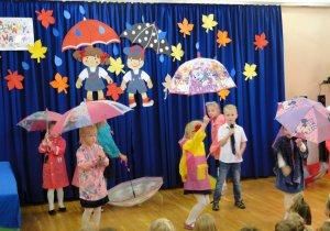 Dzieci wykonują układ taneczny z parasolkami pt:"Deszczowa piosenka"