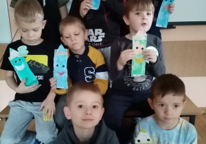 Chłopcy prezentują swoje prace plastyczne- kredki z papieru.