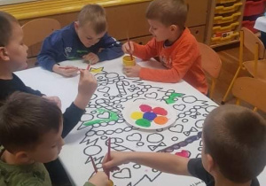 Dzieci kolorują szablon choinki kolorowymi farbami