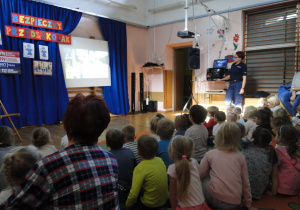 Przedszkolaki wspólnie z panią policjantką oglądają i słuchają prezentacji multimedialnej.