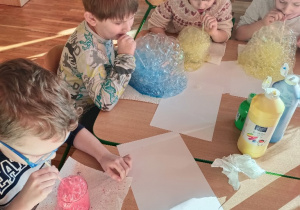 Dzieci przez słomki dmuchają do swoich szklanek z których wydobywa się kolorowa piana