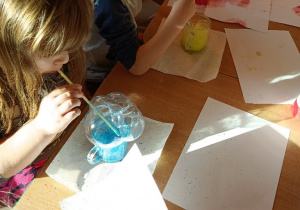 Dzieci przez słomki dmuchają do swoich szklanek z których wydobywa się kolorowa piana