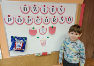 Chłopiec na tle tablicy z napisem "Dzień Popcornu"