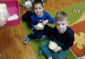 Chłopcy jedzą popcorn z małych papierowych torebek