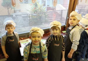 Grupka dzieci w kucharskich czapkach pozuje do zdjęcia