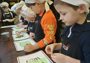 Dzieci ozdabiają piegami z białej czekolady swoje czekoladowe rysunki