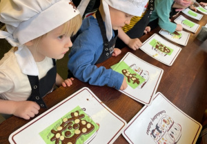Dzieci dekorują wykonane rysunki z czekolady