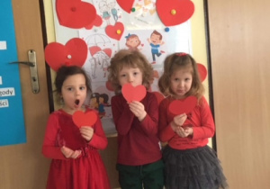 Dzieci pozują do pamiątkowego zdjęcia z serduszkami z czerwonego papieru