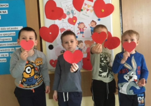 Dzieci pozują do pamiątkowego zdjęcia z serduszkami z czerwonego papieru