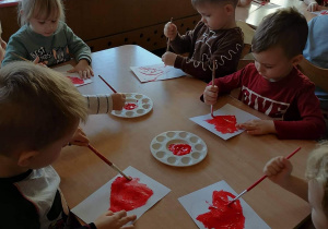 Dzieci malują serduszka farbami
