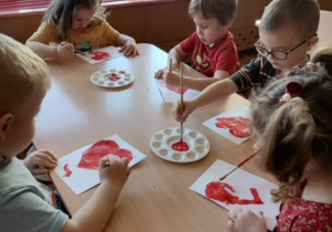 Dzieci malują serduszka farbami