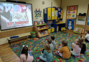 Dzieci oglądają na dużym ekranie film edukacyjny o kotach