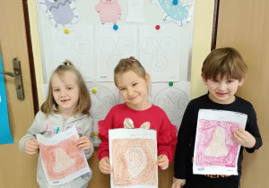 Dzieci pokazują swoje pokolorowane obrazki.
