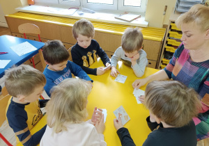 Dzieci grają z panią w grę stolikową z Czyściochowa "Szybko znajdź parę"