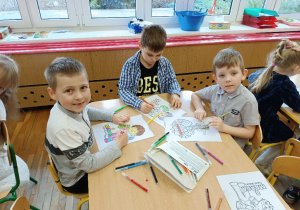 Dzieci przy stolikach kolorują obrazki