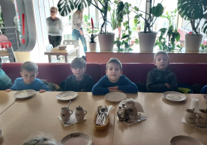 Dzieci siedzą przy stoliku czekając na pizzę