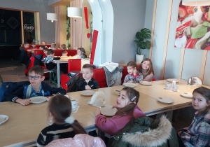 Dzieci siedzą przy stoliku czekając na pizzę