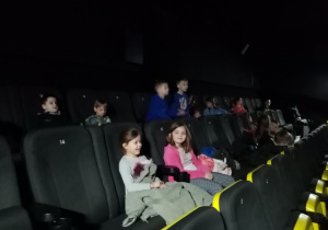 Dzieci siedzą w fotelach i czekają na film.