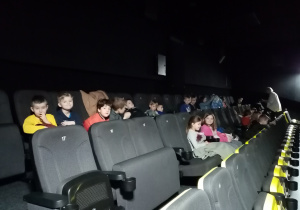 Dzieci siedzą w fotelach i czekają na film.