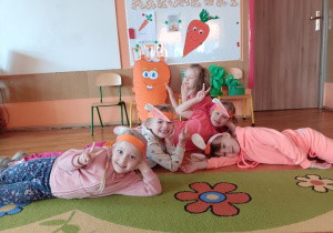 Dziewczynki leżą na podłodze z opaskami marchewek
