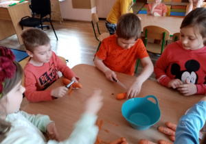 Chłopcy obierają i kroją marchewkę.