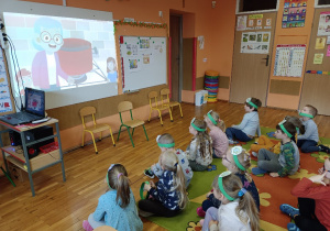 Dzieci oglądają film edukacyjny na dużej tablicy