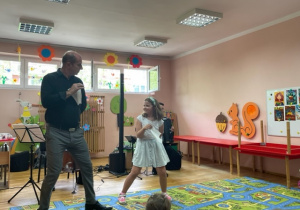 Dziewczynka wraz z panem Maciejem tańczą w rytm muzyki