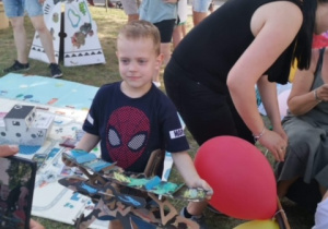 Dziecko prezentuje pomalowany przez siebie papierowy samolot