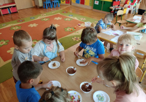 Dzieci z grupy 3 zdobią ciasteczka płynną czekoladą i kolorowymi cukiereczkami