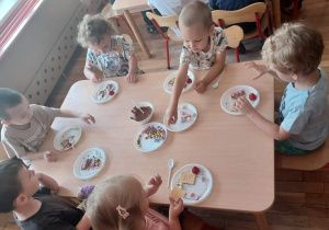 Dzieci z grupy 1 zdobią ciasteczka płynną czekoladą i kolorowymi cukiereczkami