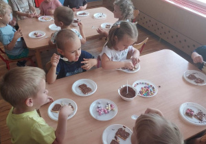 Dzieci z grupy 1 zdobią ciasteczka płynną czekoladą i kolorowymi cukiereczkami