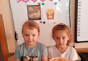 Dziewczynki pokazują frytki wykonane z ziemniaków i marchewki.