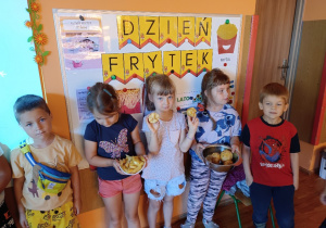 Dzieci stoją na tle napisu Dzień Frytek trzymając ziemniaki