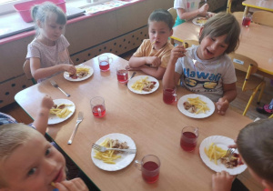 Dzieci jedzą obiad w skład, którego wchodzą frytki.