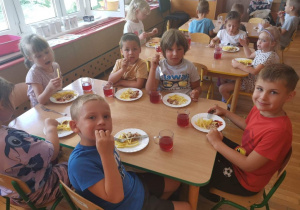 Dzieci jedzą obiad w skład, którego wchodzą frytki.