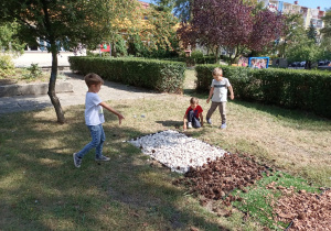 Dzieci bawiące się w ogrodzie przy ścieżce sensorycznej
