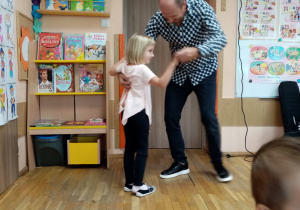 Pan Maciej tańczy z dziewczynką w rytm muzyki.