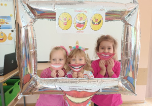 Pamiątkowe zdjęcie w ramce trójki dzieci z papierowymi uśmiechami