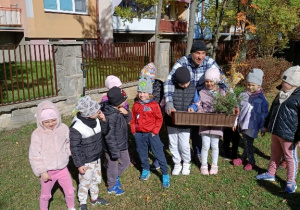 Dzieci z panem Rafałem trzymają skrzynkę z sadzonkami