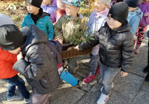 Dzieci niosą w pojemniku sadzonki drzew