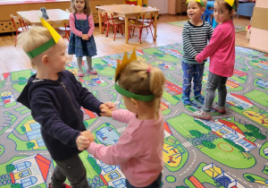 Dzieci w koronach na głowie tańczą parami.