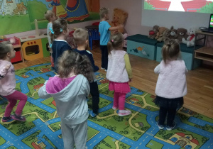 Dzieci naśladują ruchy przedstawiane na tablicy.