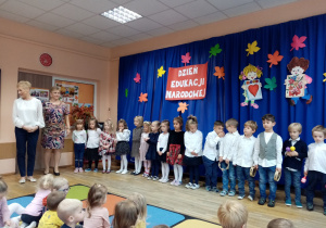 Grupa „Słoneczka” wraz z nauczycielkami na tle dekoracji Dzień Edukacji Narodowej.