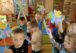 Dzieci pokazują wykonane przez siebie wiatraczki z papieru.