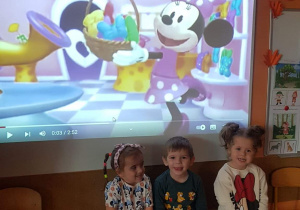 Dzieci w strojach związanych z Myszką Miki na tle bajki „Miki i przyjaciele”.
